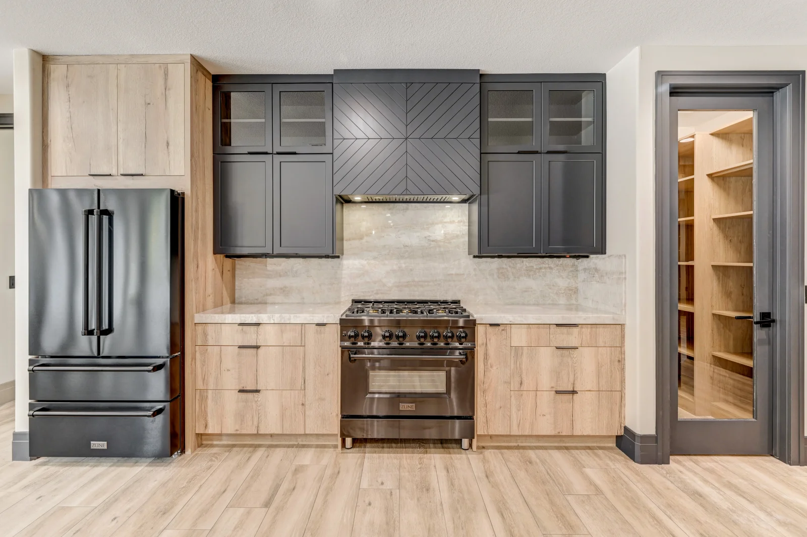 Modern kitchen with light wood and gray cabinets, stainless steel appliances, quartz counters, geometric backsplash