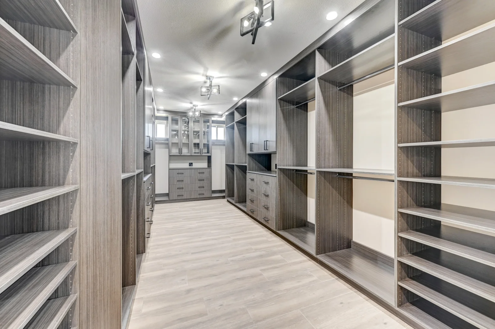 Custom walk-in closet with gray cabinetry, white shelves, drawers, and full-length mirror