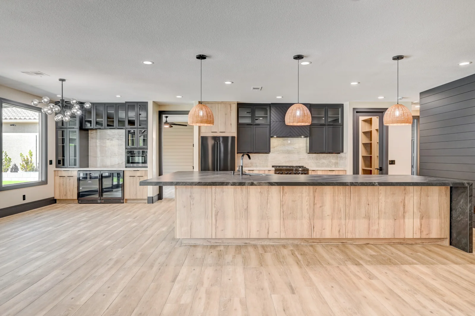 Modern kitchen with wood and gray cabinetry, quartz counters, stainless appliances, pendant lights, and luxury vinyl flooring