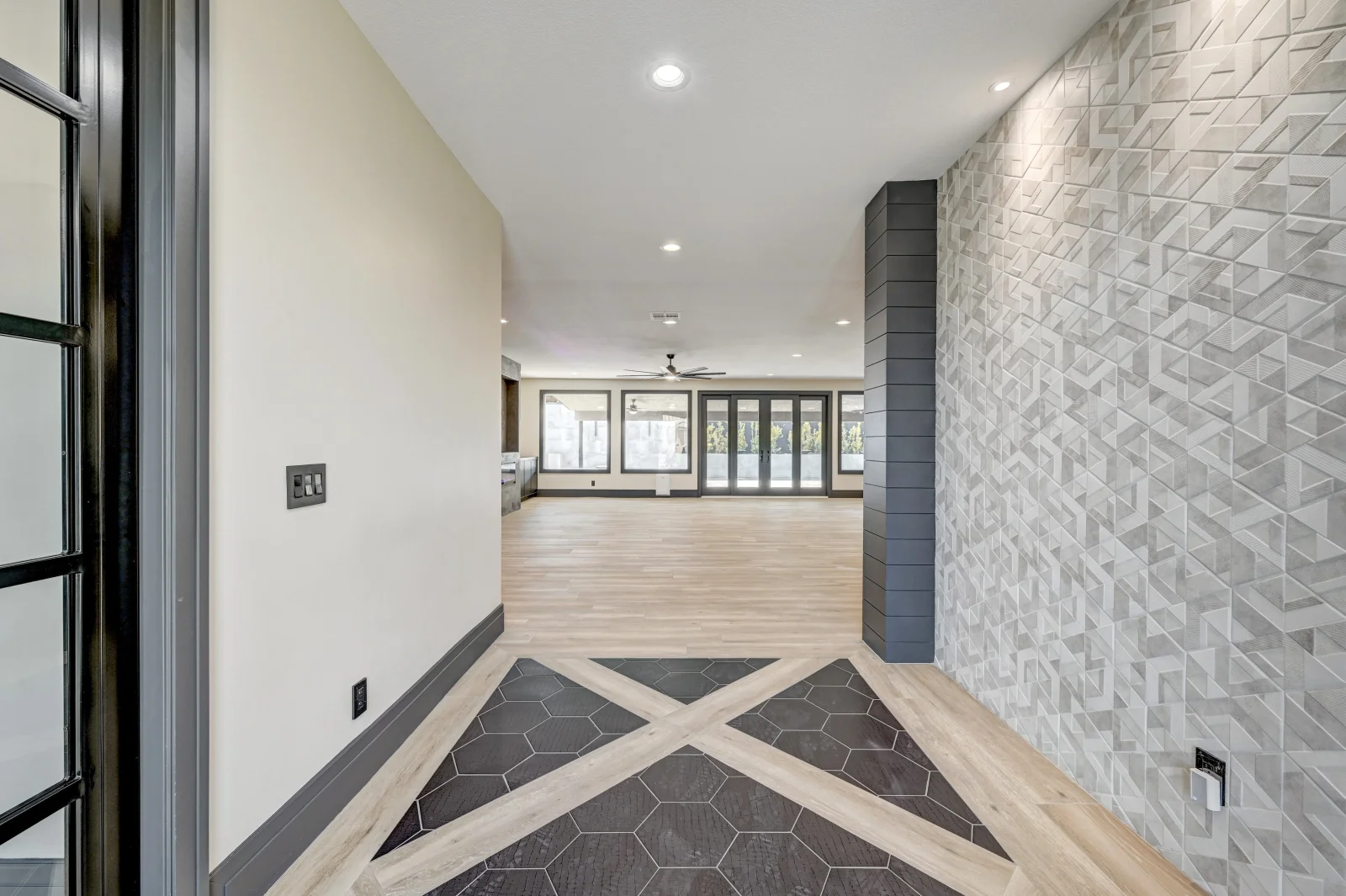Entryway with geometric hexagonal and wood tile flooring, 3D textured wall, recessed lighting, and glass doors