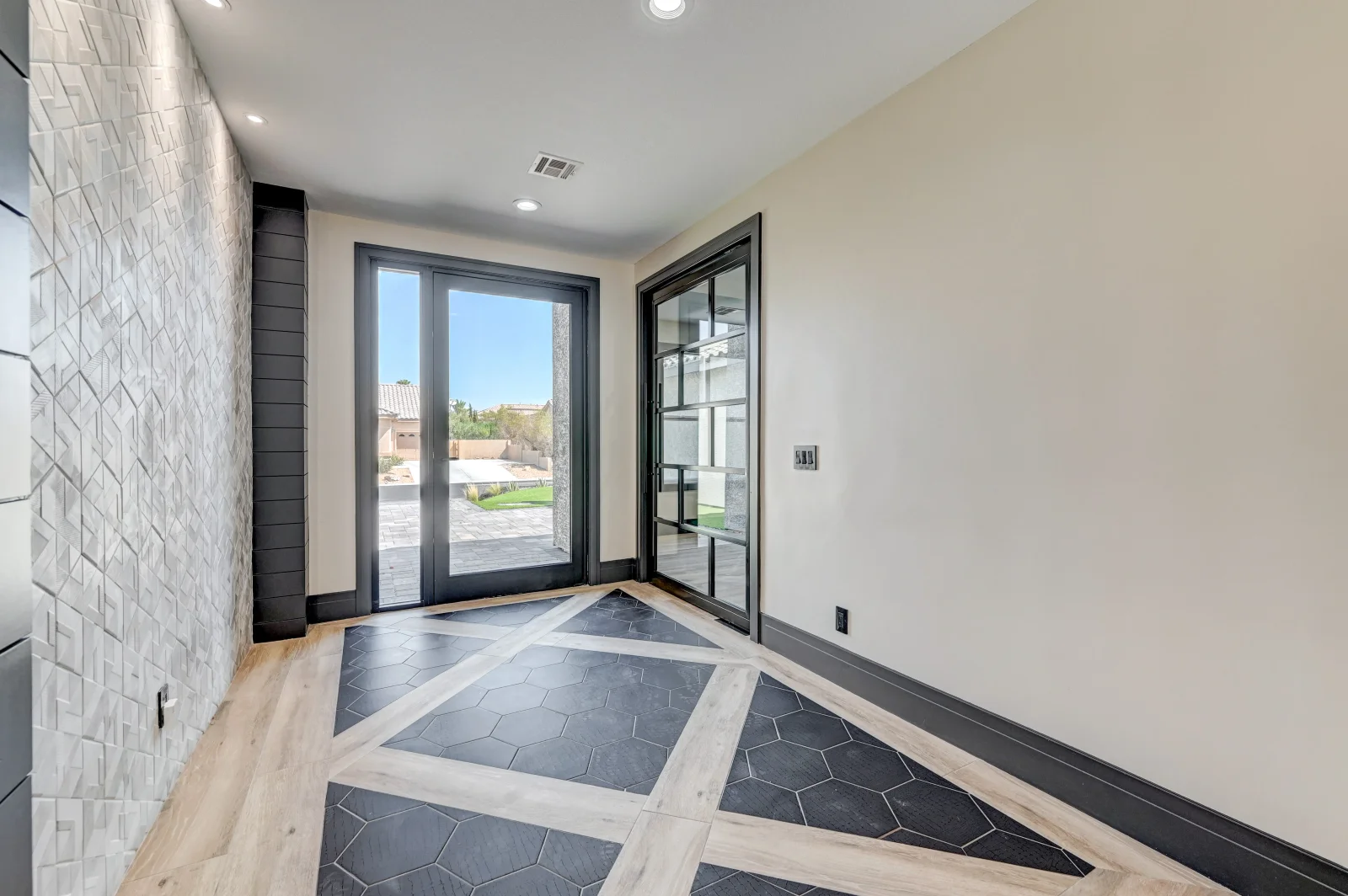 Entryway with hexagonal tile, wood plank flooring, black-framed glass doors, and white shiplap wall